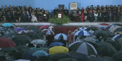 People sitting in the rain with umbrellas at inauguration of Harvard President Claudine Gay
