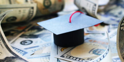 A graduation cap sitting on top of a pile of money